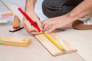 Cropped hand of a carpenter taking measurement of a wooden plank